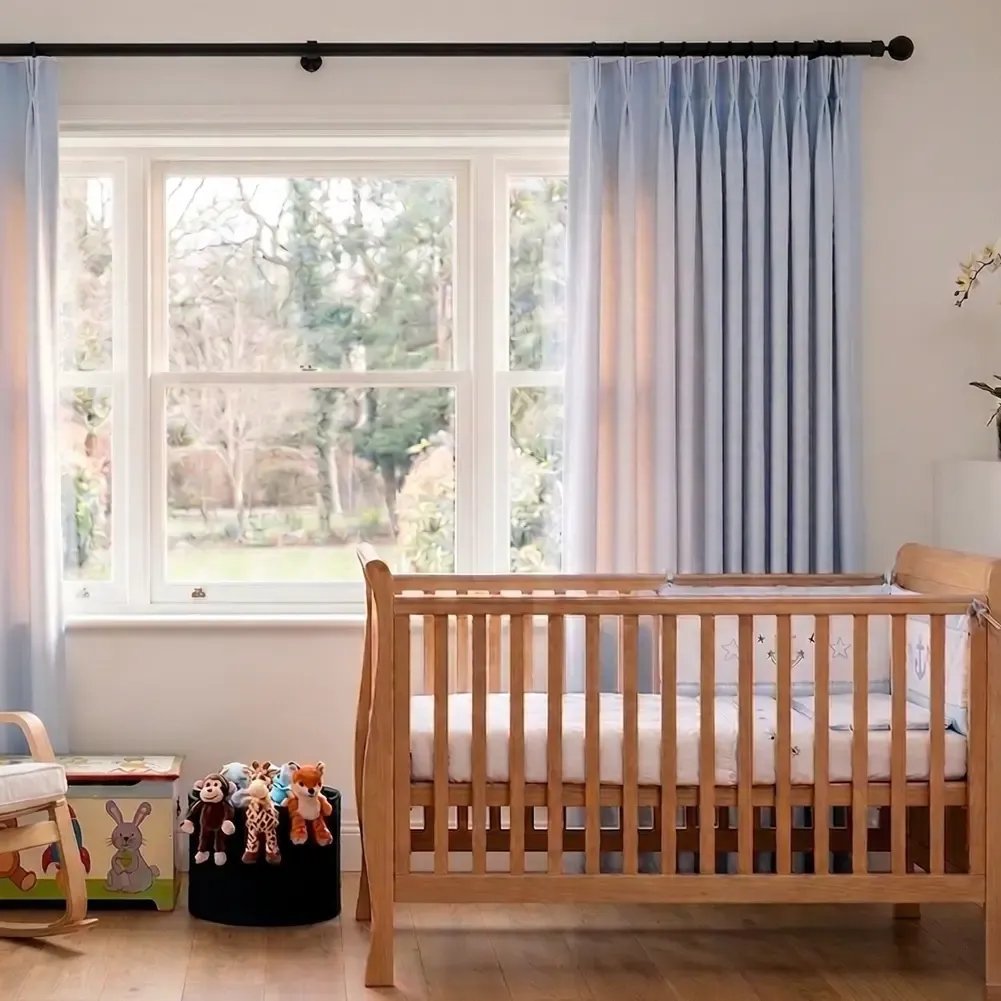 Side-angle view of a 28mm wrought iron single curtain pole in matt black, featuring a classic ball finial and a sturdy matching wall bracket in a contemporary room.